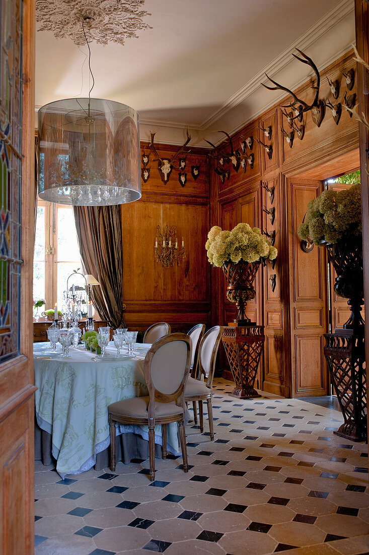 Stilvolles Speisezimmer mit Holzwänden, Blumenschmuck und Tiergeweihen als Deko