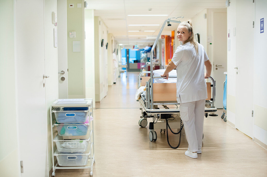 Nurse pushing hospital bed in corridor