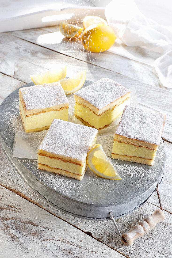 Vier Stücke Zitronen-Käsekuchen mit Puderzucker