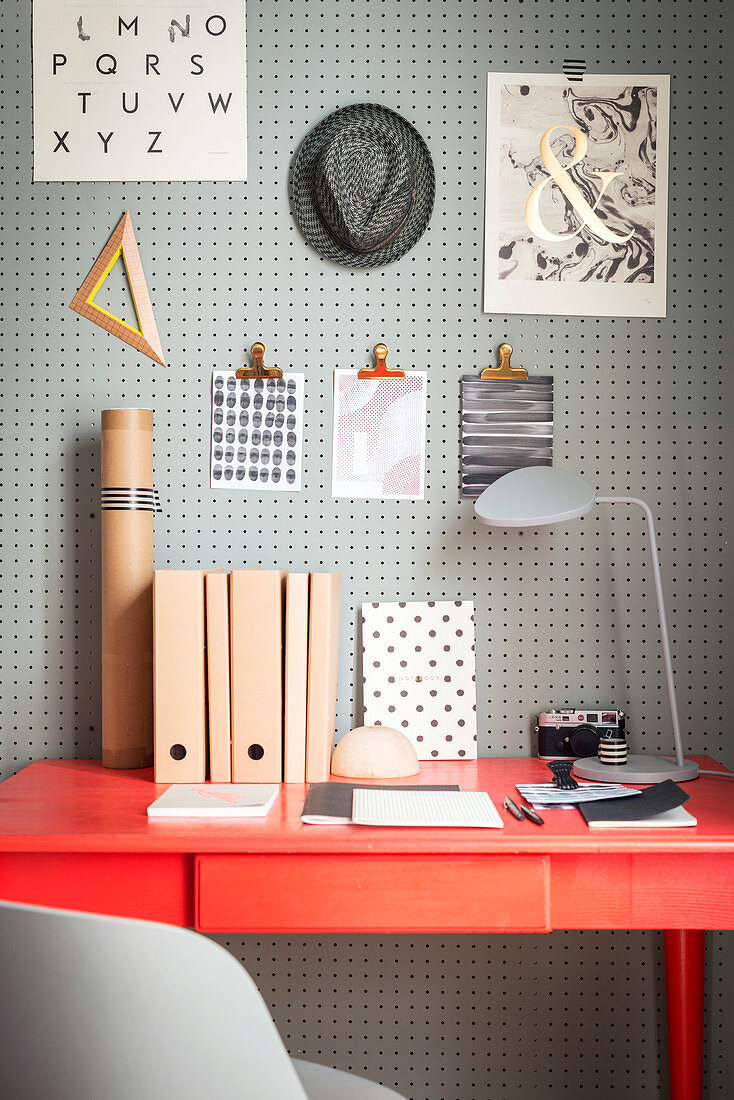 Perforated wooden panel used as note board above desk in study