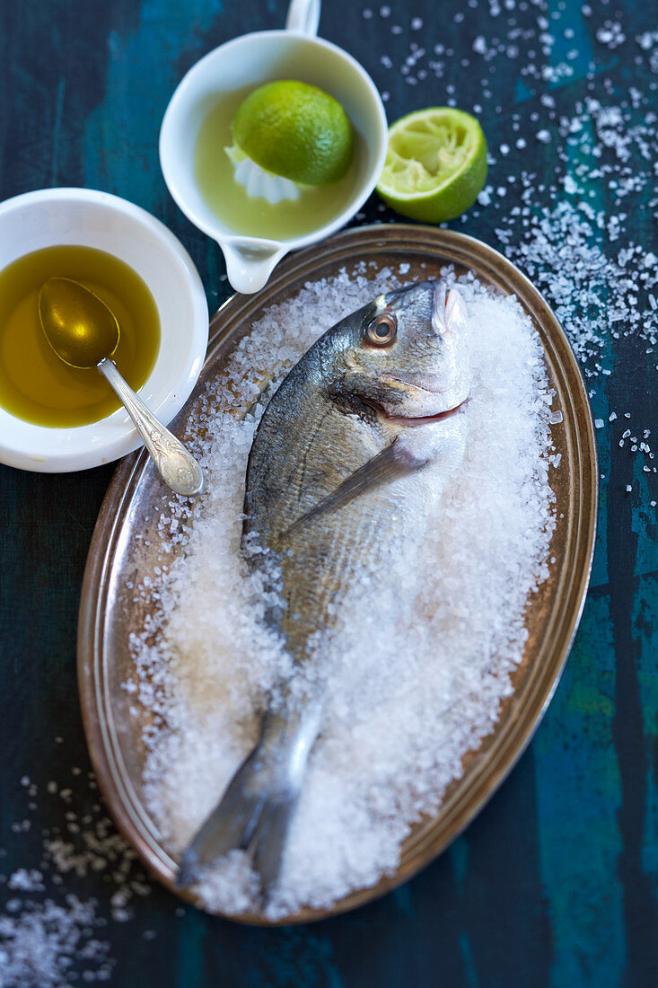 Sea bream in salt with olive oil and limes