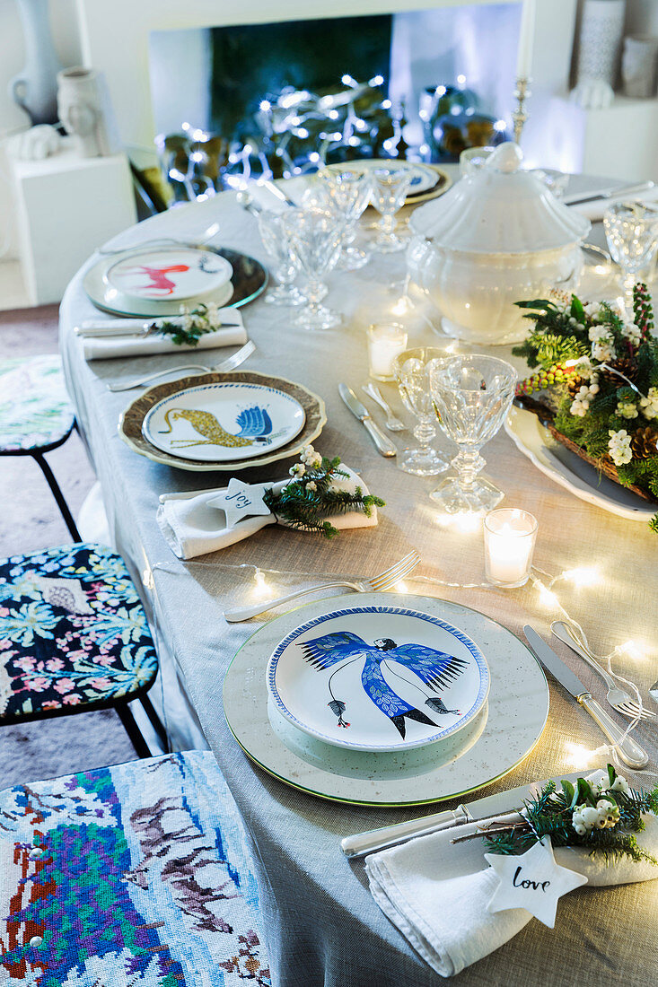 Table festively set with flower arrangement, fairy lights and individual underplates