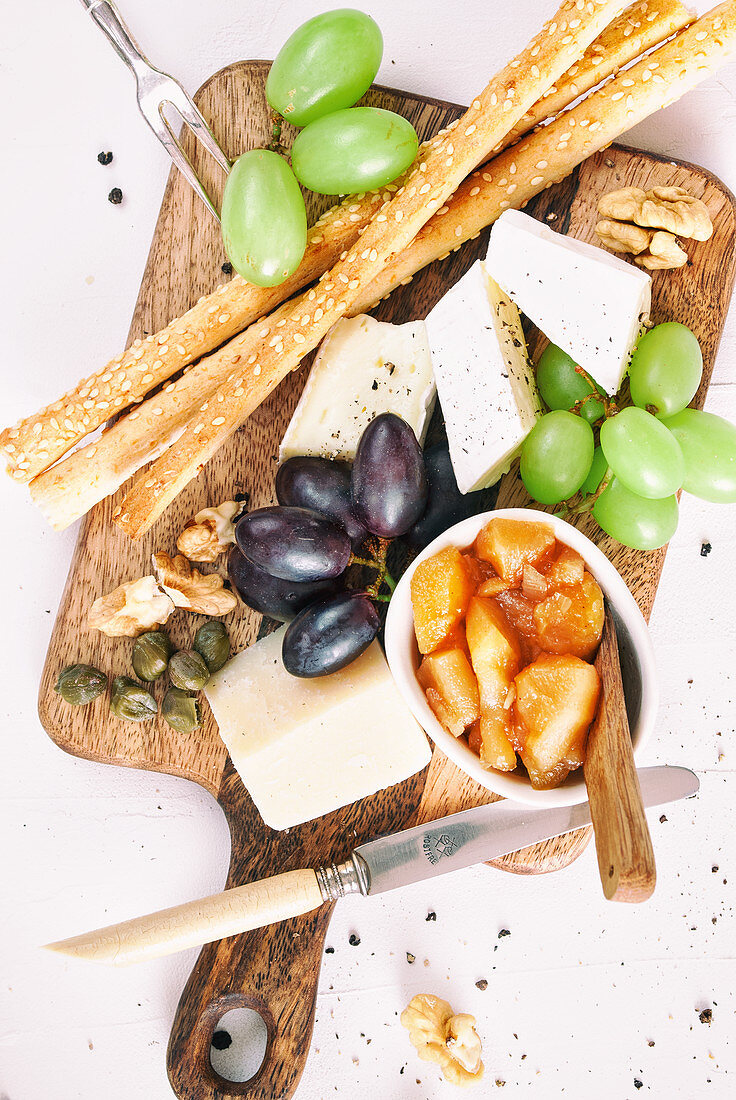 Cheese platter with apple chutney, nuts, capers, grapes and breadsticks