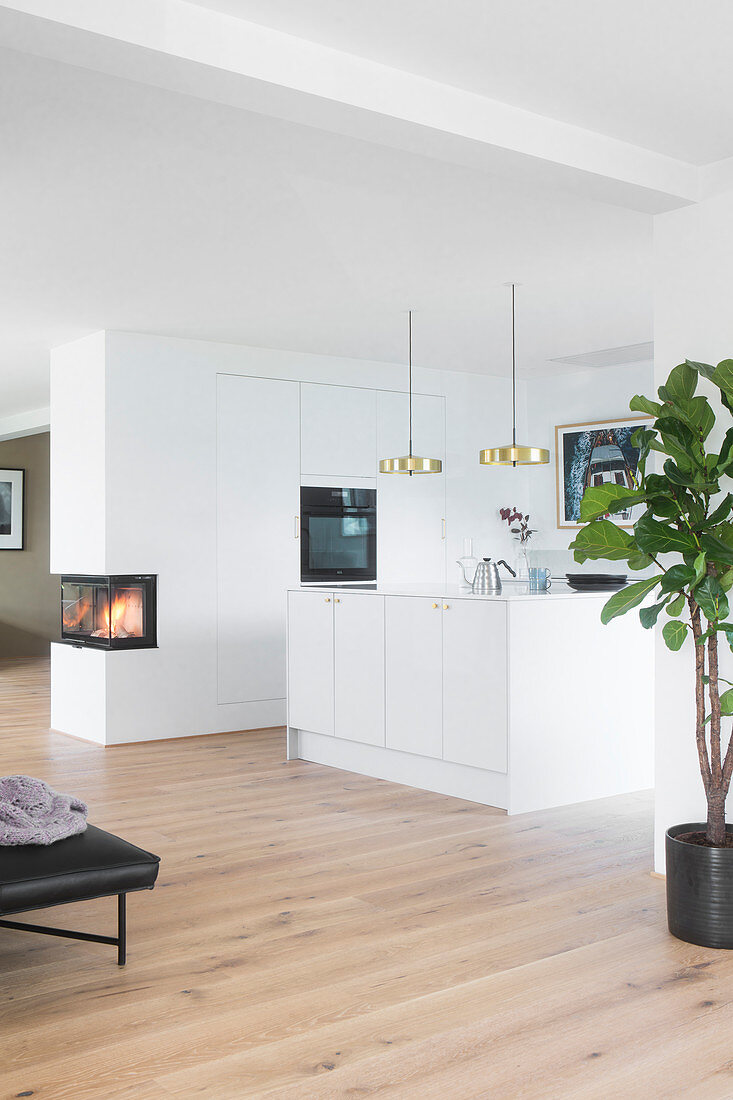 Island counter and white fitted kitchen in open-plan interior