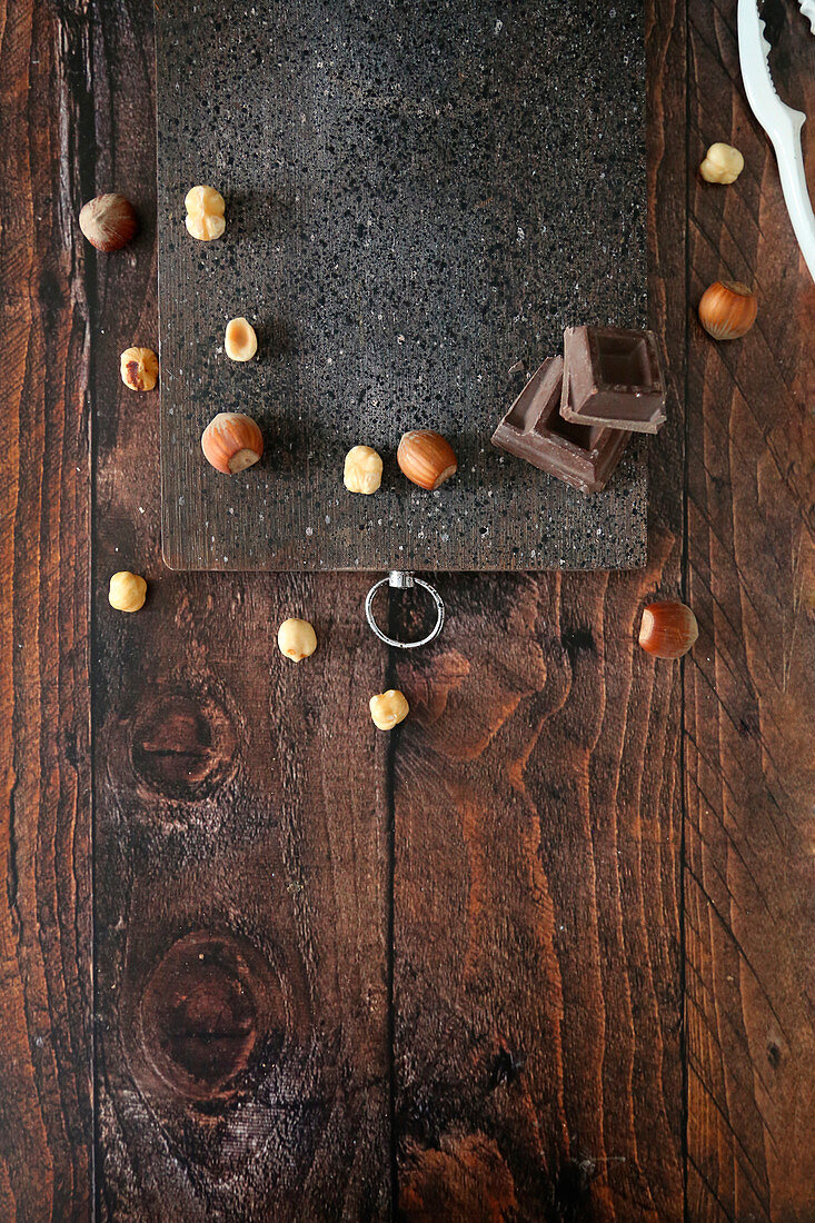 Wooden cutting board on table with hazelnuts and chocolate