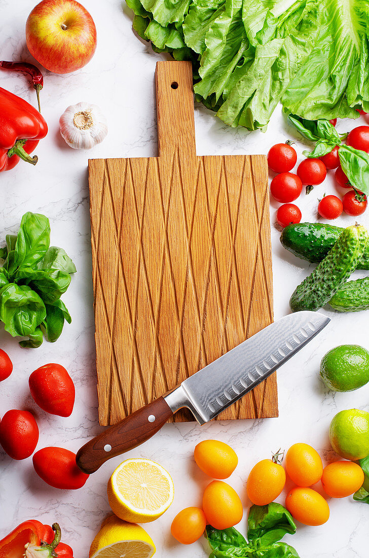 Fresh vegetables, salad leaves and greens and cutting board with chefs knife