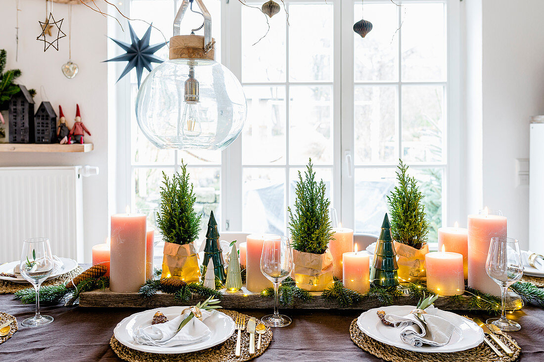 Table set for Christmas with small potted conifers and pillar candles