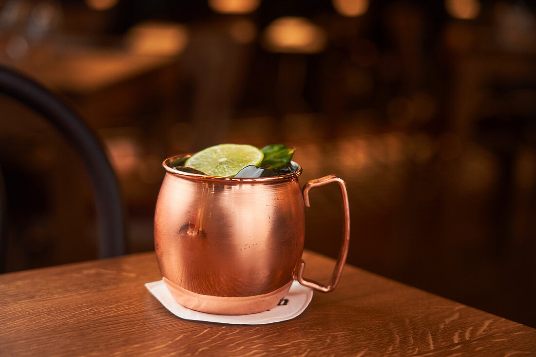 Moscow Mule served in copper mug decorated with lemon slice on wooden table
