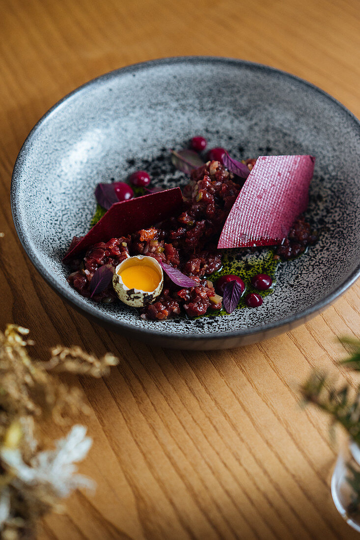 Saladbowl made with marinated herring and wild red lingonberries garnished with raw quail egg