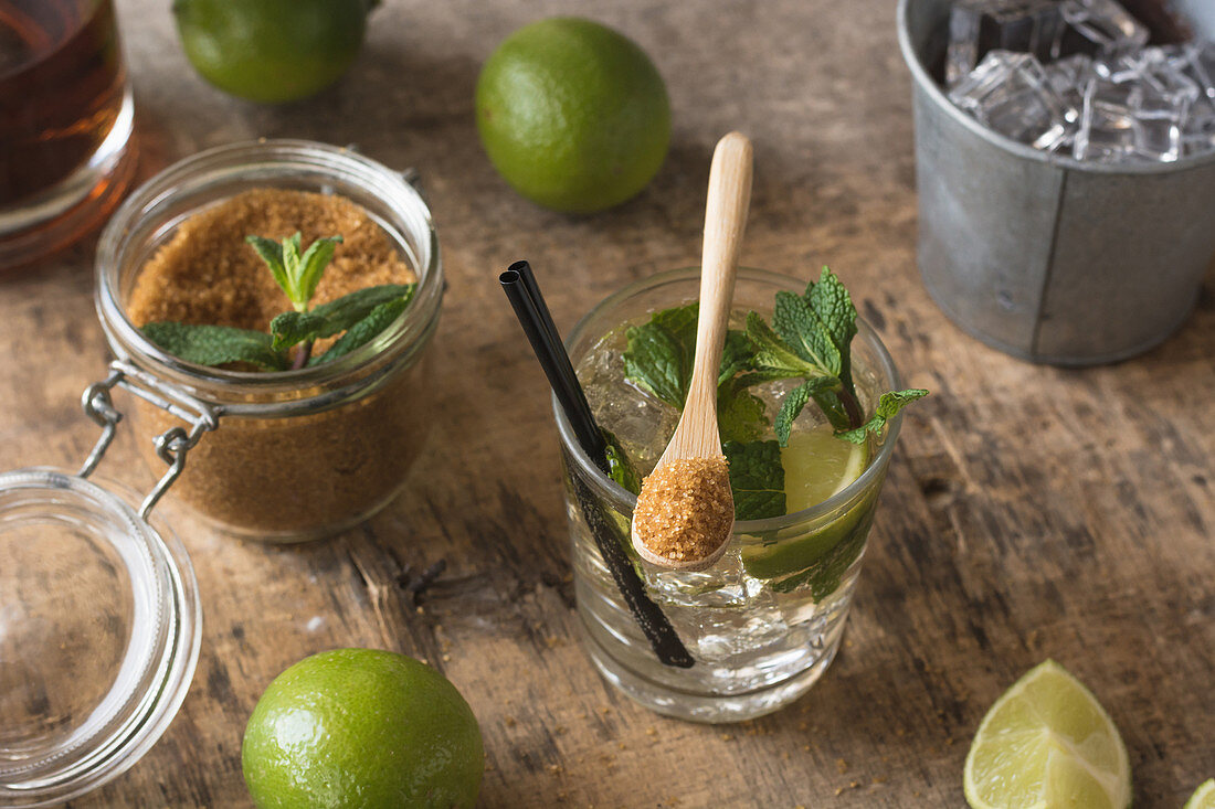 Fresh limes and peppermint leaves, rum and brown sugar for mojito preparation
