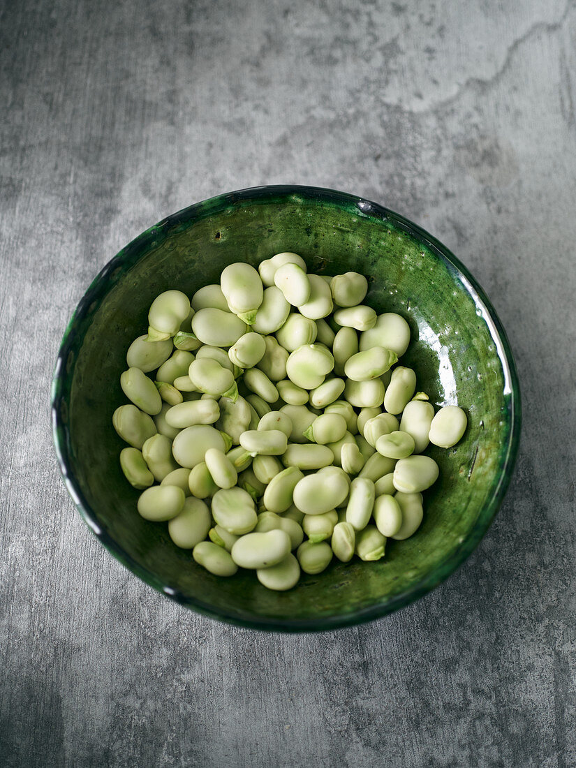 Fresh broad beans in a green ceramic bowl