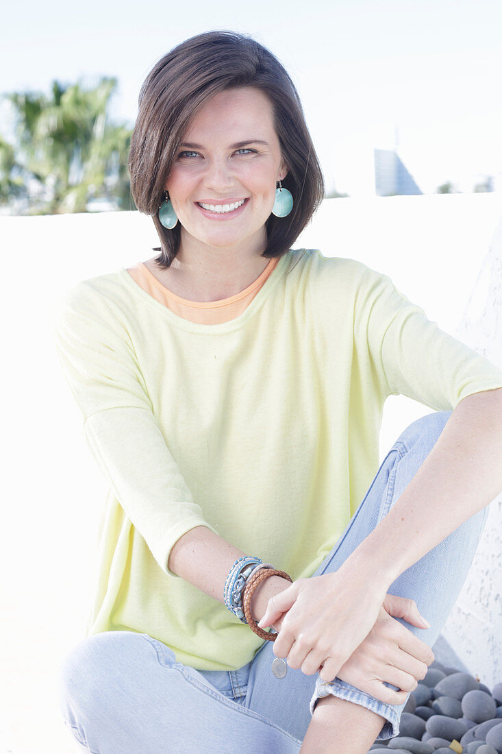 A young woman wearing an apricot top, a yellow jumper and jeans