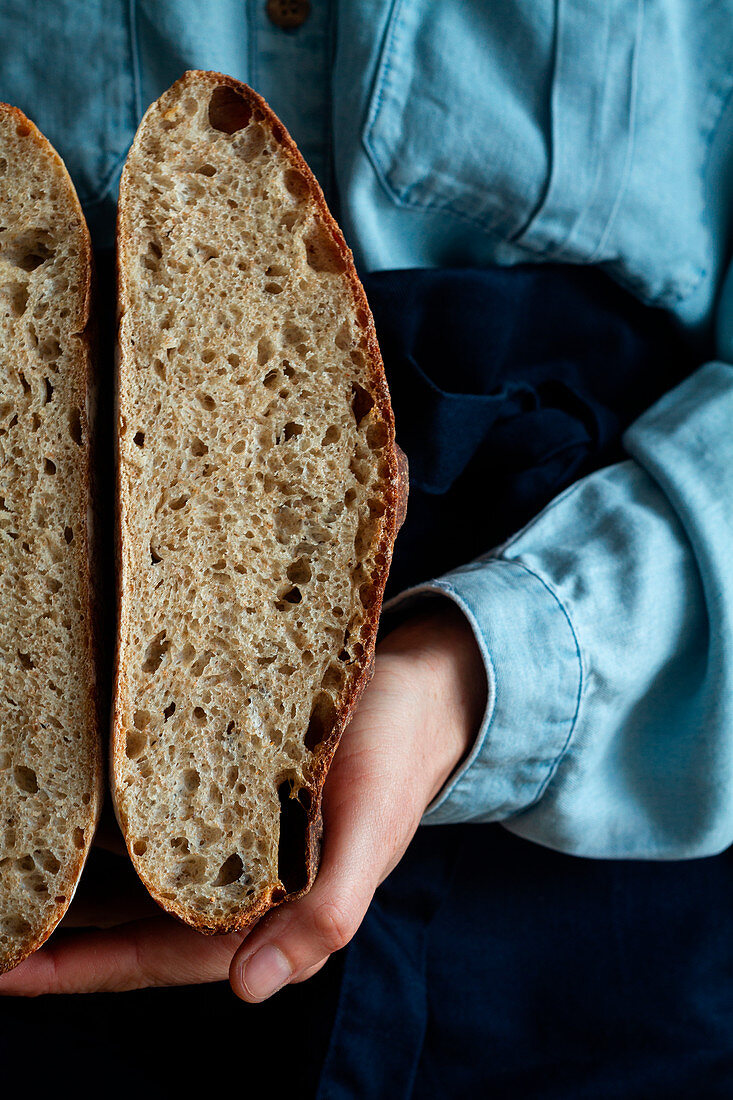 Woman in apron holding slice homemade sourdough bread