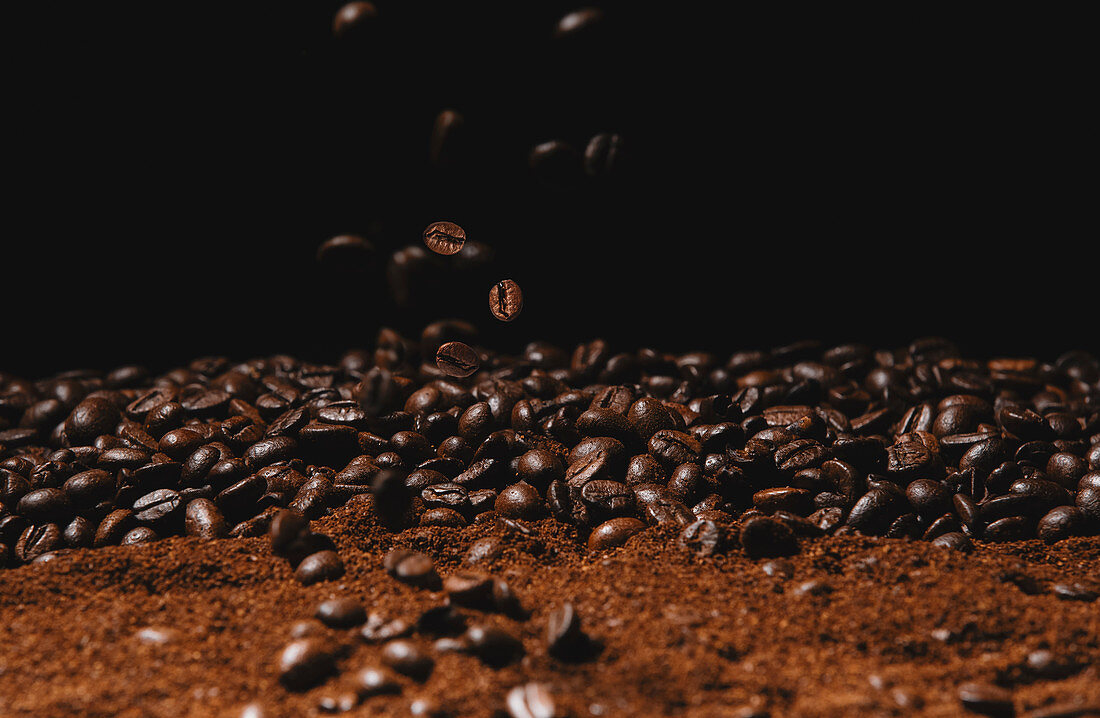 Kaffeestilleben mit fallenden Kaffeebohnen und Kaffeepulver