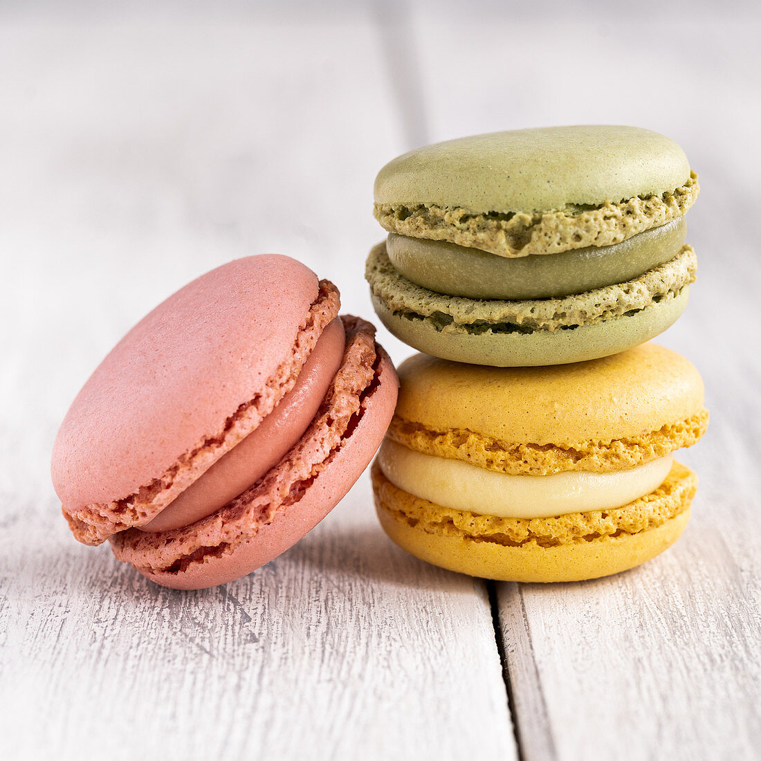 Colorful macaroons stacked in pile against wooden white surface