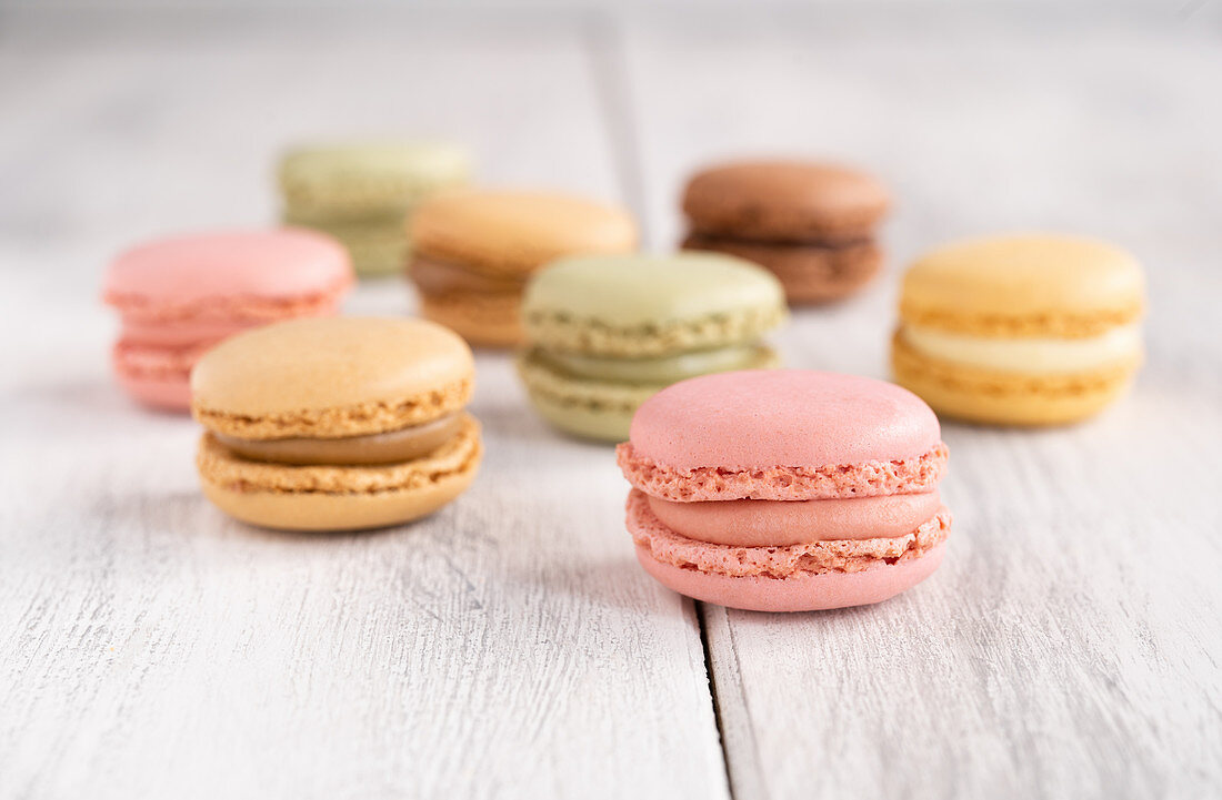 Colorful macaroons stacked in pile against wooden white surface