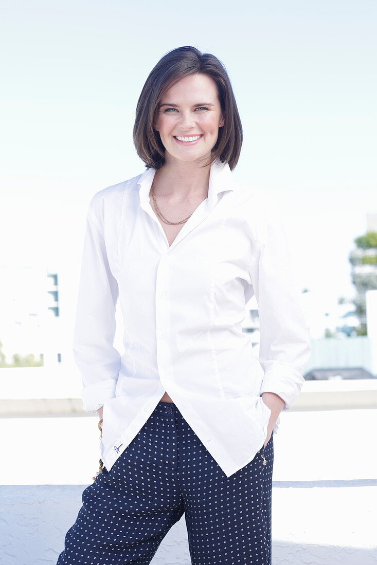 A young woman wearing a white shirt and polka dot trousers