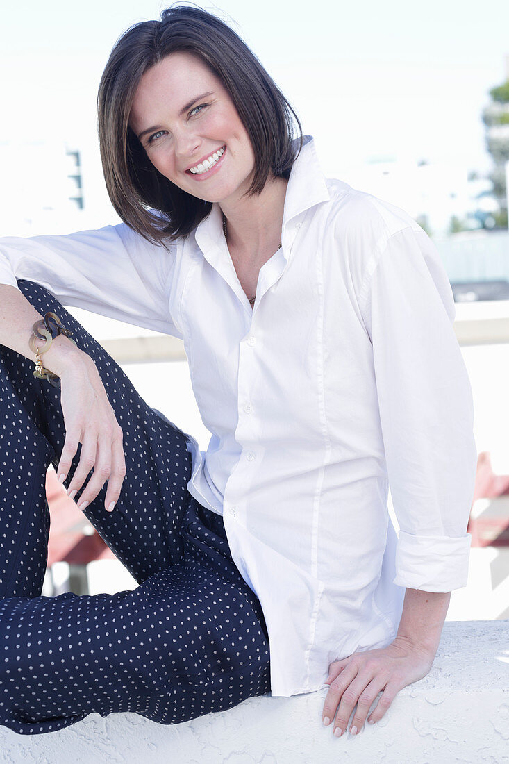 A young woman wearing a white shirt and polka dot trousers