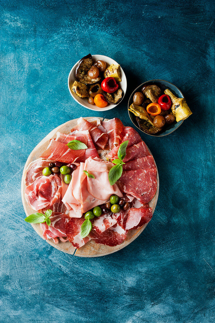 Cold cuts with olives and marinated vegetables in small bowls