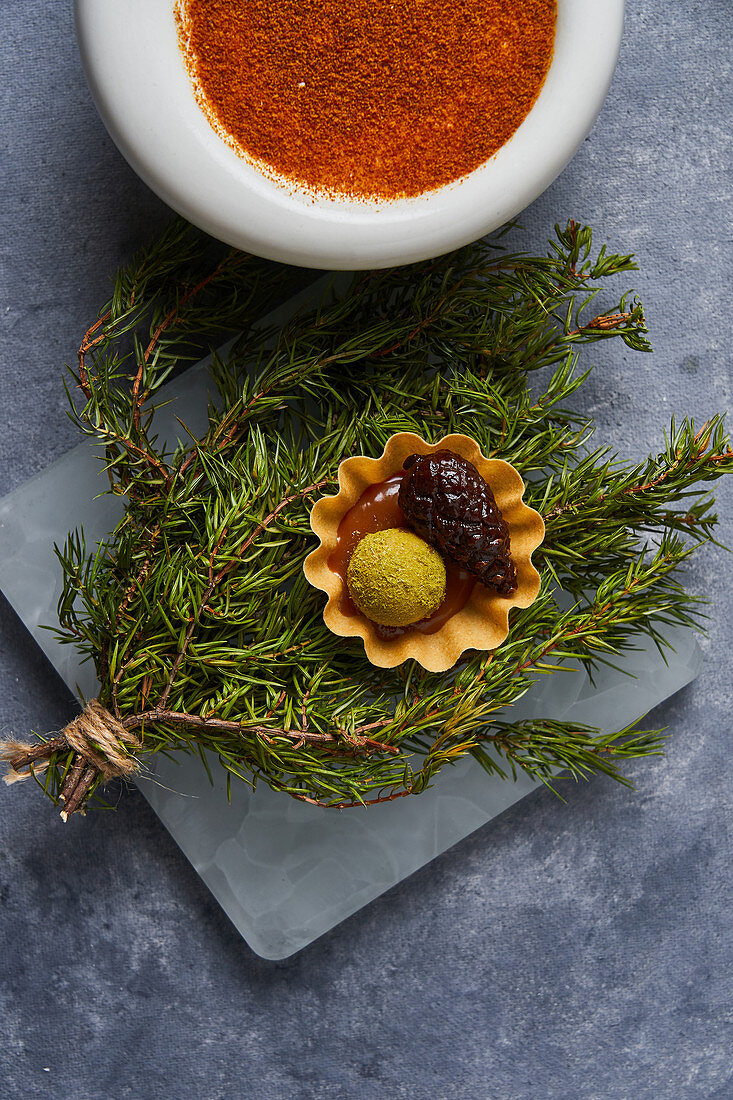 Fresh conifer twigs with pickled cone and boiled egg yolk, bowl with paprika