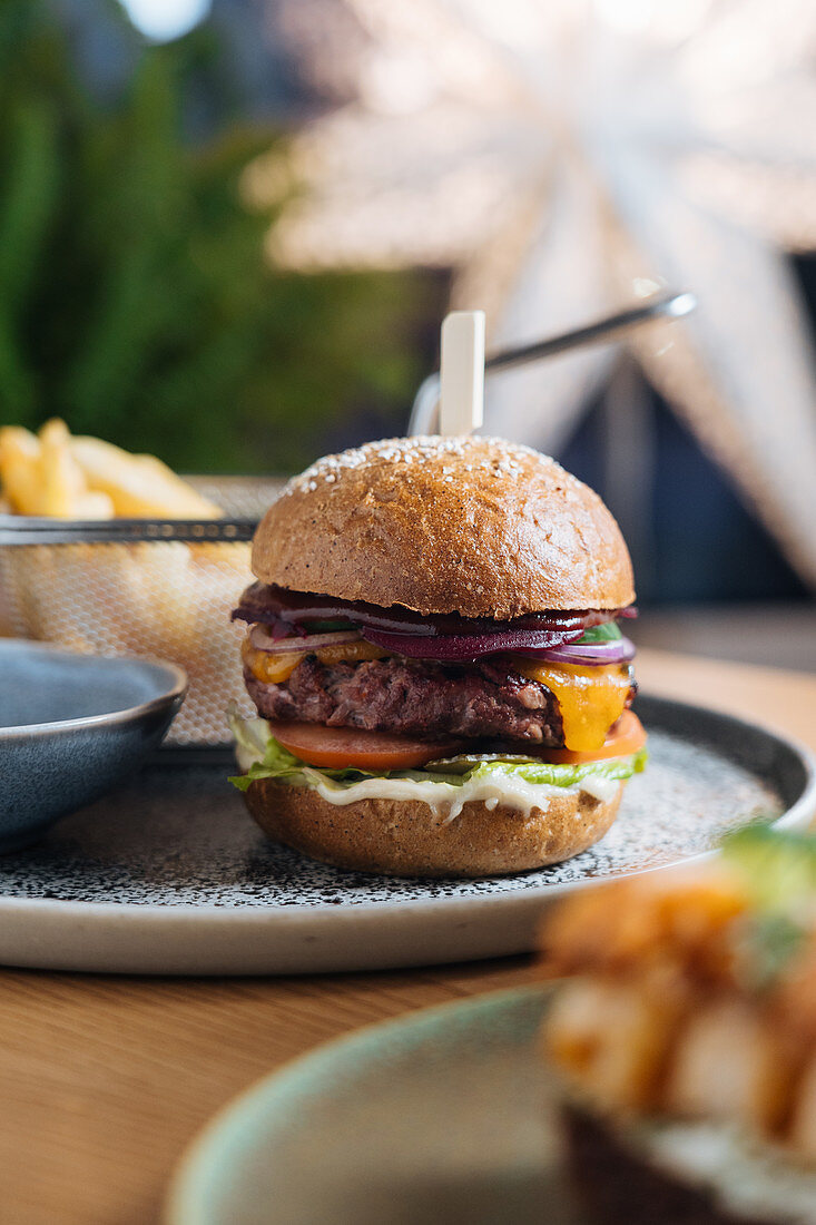 Burger with patty of fresh rye bread rolls, red onion, cheese, tomatoes, lettuce leaf and sauce