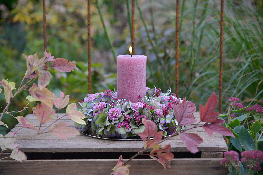 A wreath of candles made from hydrangea blossoms, autumn chrysanthemums, bell heath, and snowberries