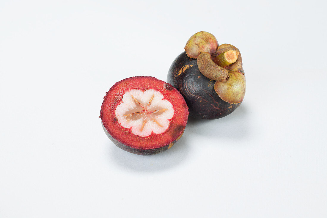 Mangosteen, whole and halved on a white background