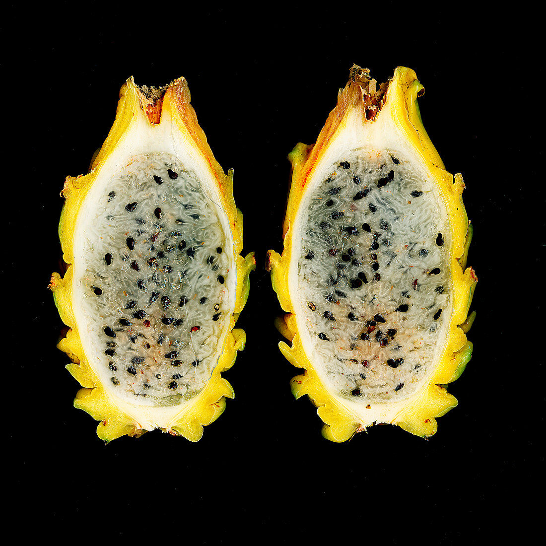 A sliced yellow pitahaya against a black background