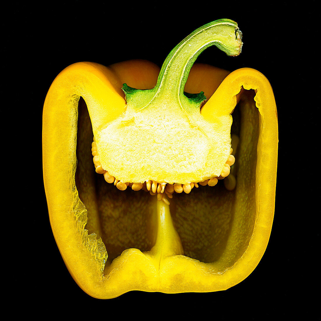 A sliced yellow pepper against a black background