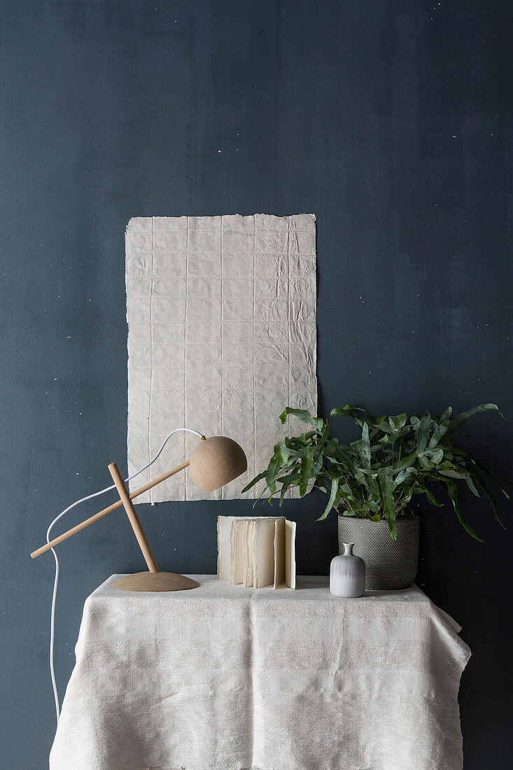 Still-life arrangement with table lamp and houseplant against dark blue wall