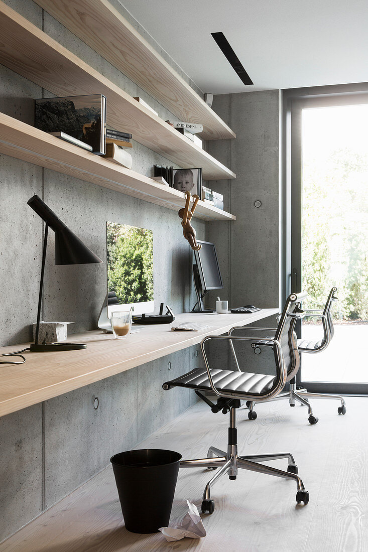 Fitted desk and shelves made from wooden boards on concrete wall