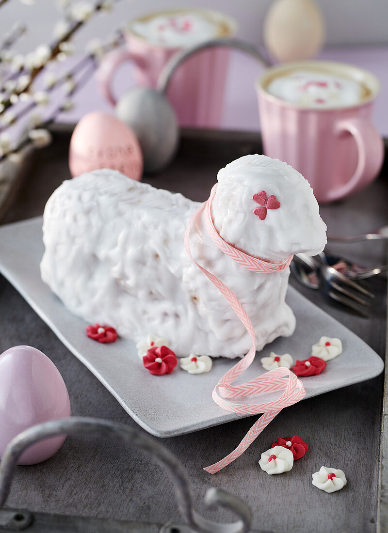 Gebackenes Osterlamm mit weißer Zuckerglasur dekoriert mit Zuckerblüten