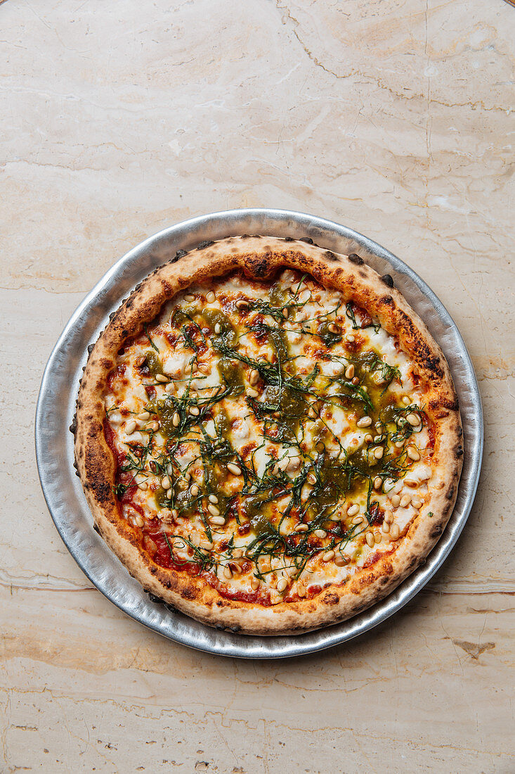 Baked vegetarian pizza served with cheese, seeds and herbs on table