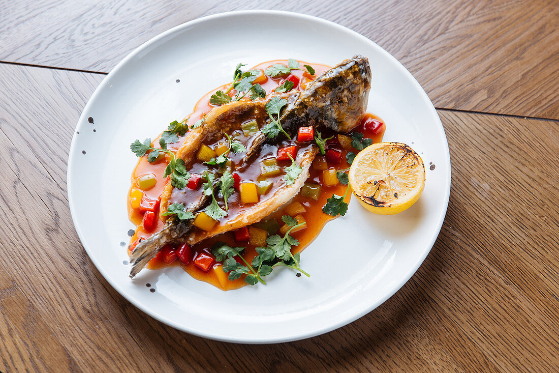 Gebratener Fisch mit Tomatensauce, Gemüse und Koriandergrün