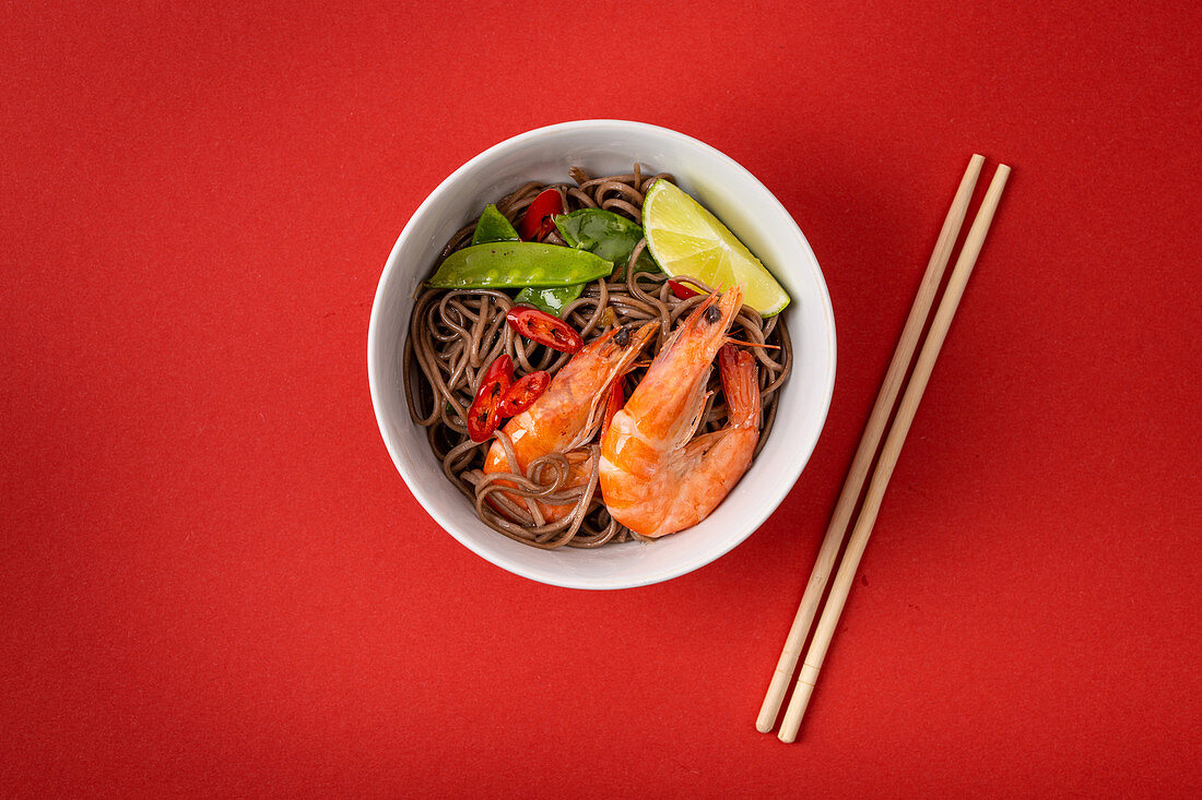 Asian stir fry soba noodles with shrimps, vegetables, green peas, red pepper