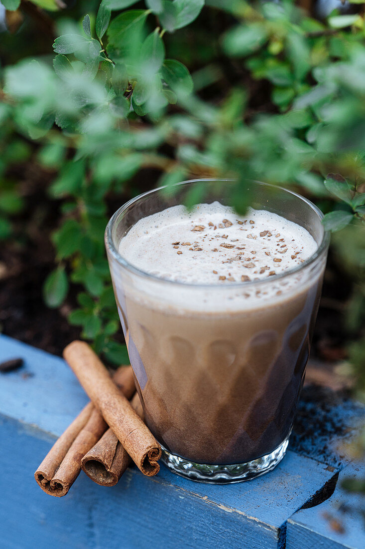 Refreshment beverage eggnog with cinnamon in glass cup on rustic surface