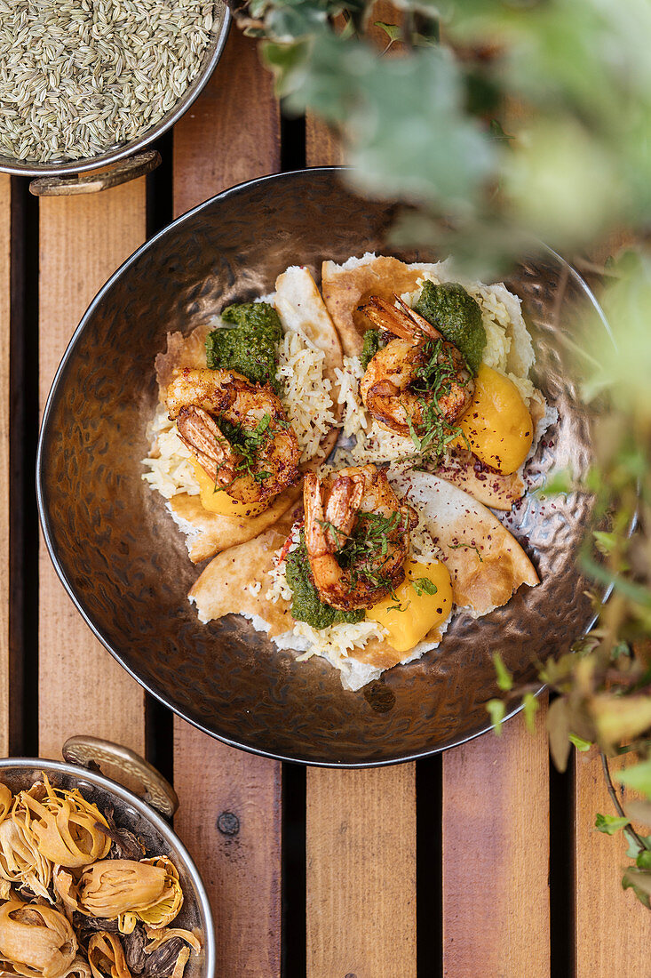 Fried eggs with shrimps covered by herbs in pan on wooden table