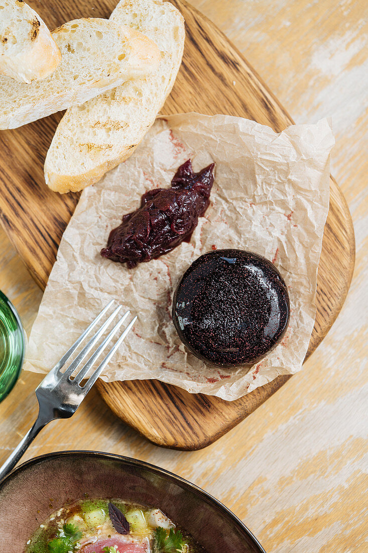 Appetizing brown jelly with berry sauce on baking paper on wooden stand