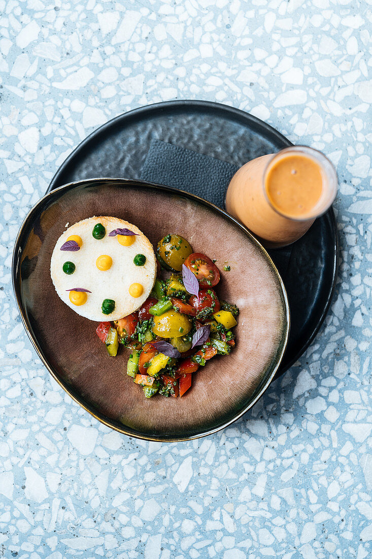 Red ripe sliced tomatoes, onion, pepper, herbs in ceramic plate on table