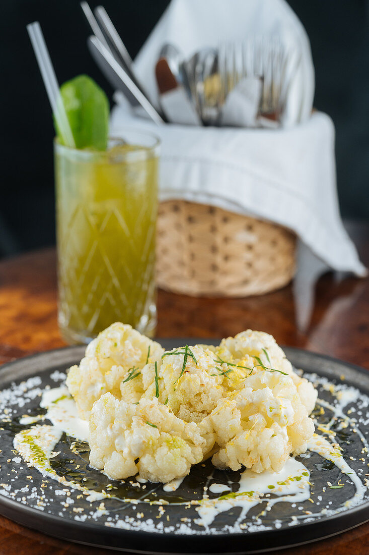 Cauliflower in sauce at table with sandwiches and fresh lemonade