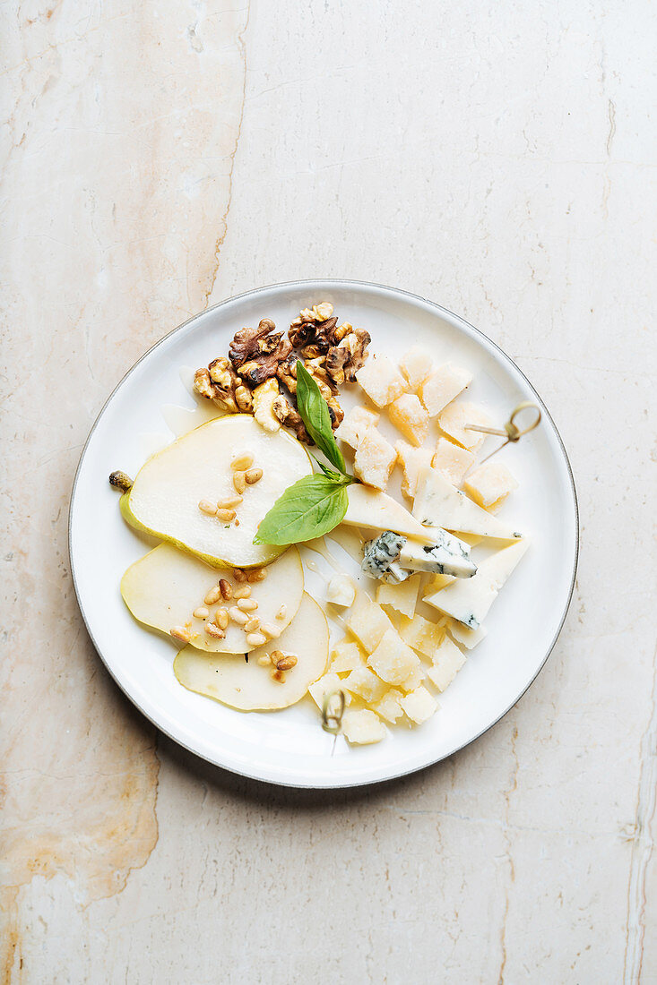 Pieces of cheese with skewers, fresh mint and slices of pear with walnut