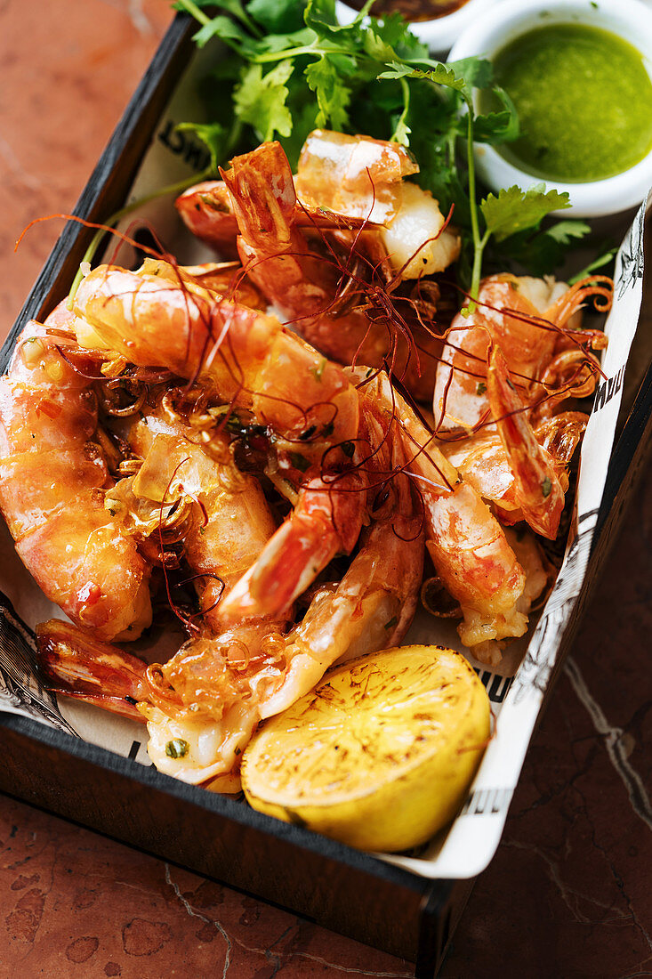 Baked big shrimps in square plate with lemon fresh parsley and green sauce