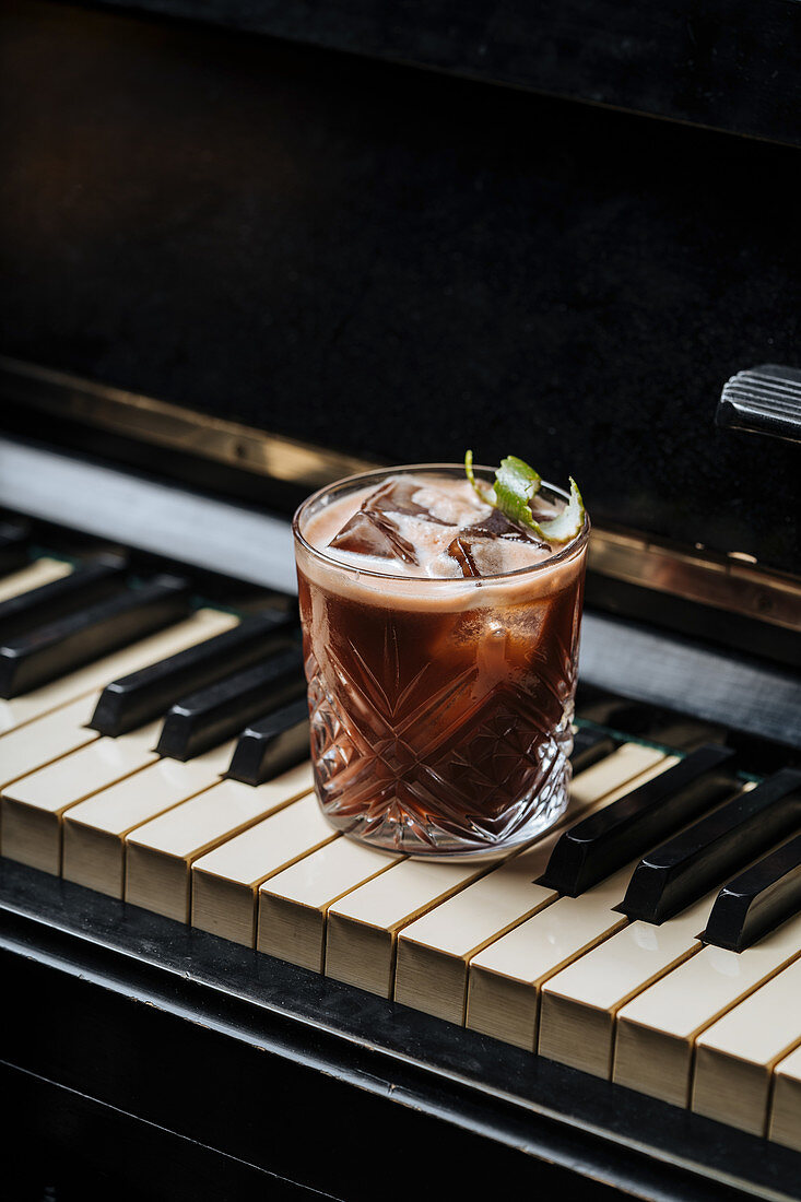Cocktail mit Eiswürfeln auf Klaviertasten