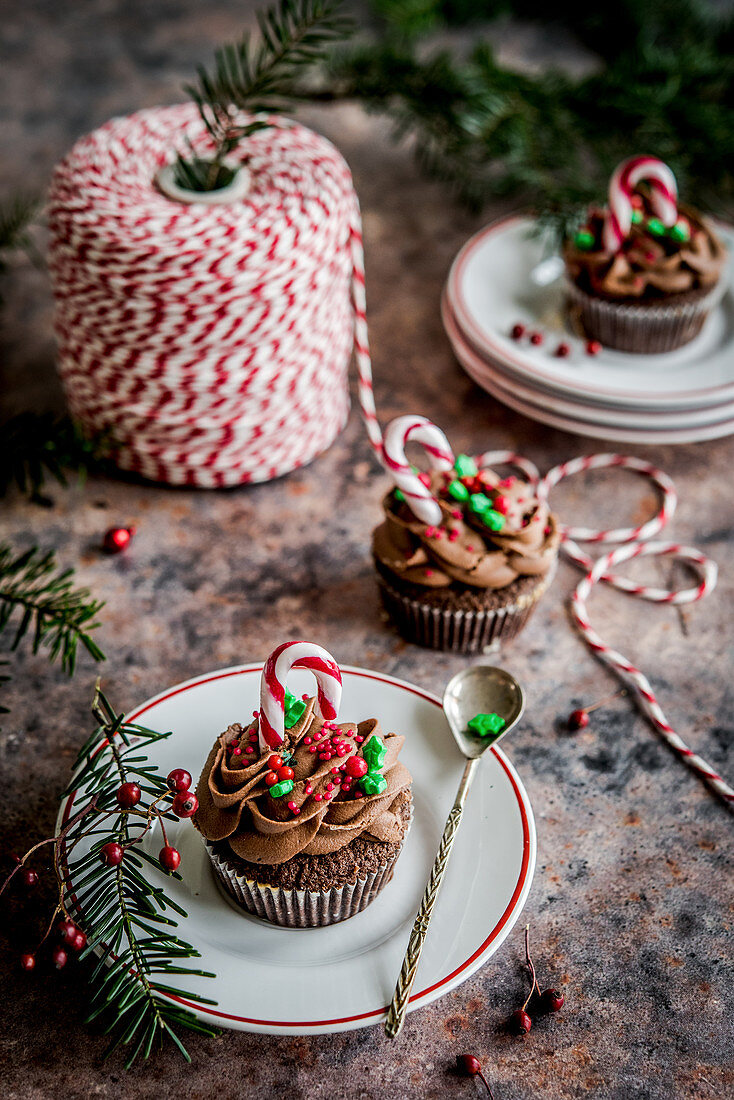Weihnachtlicher Schokoladen-Cupcakes mit Cremehaube und Zuckerstange