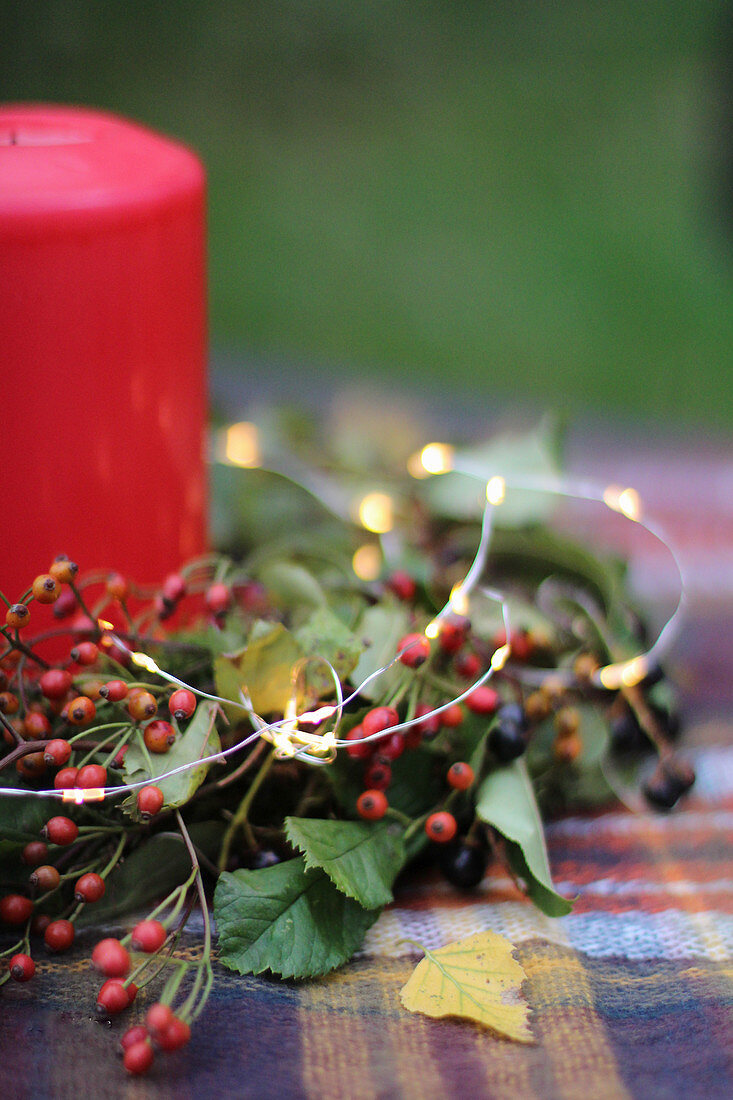 Herbstdeko mit Beerenzweigen, Lichterkette und Kerze