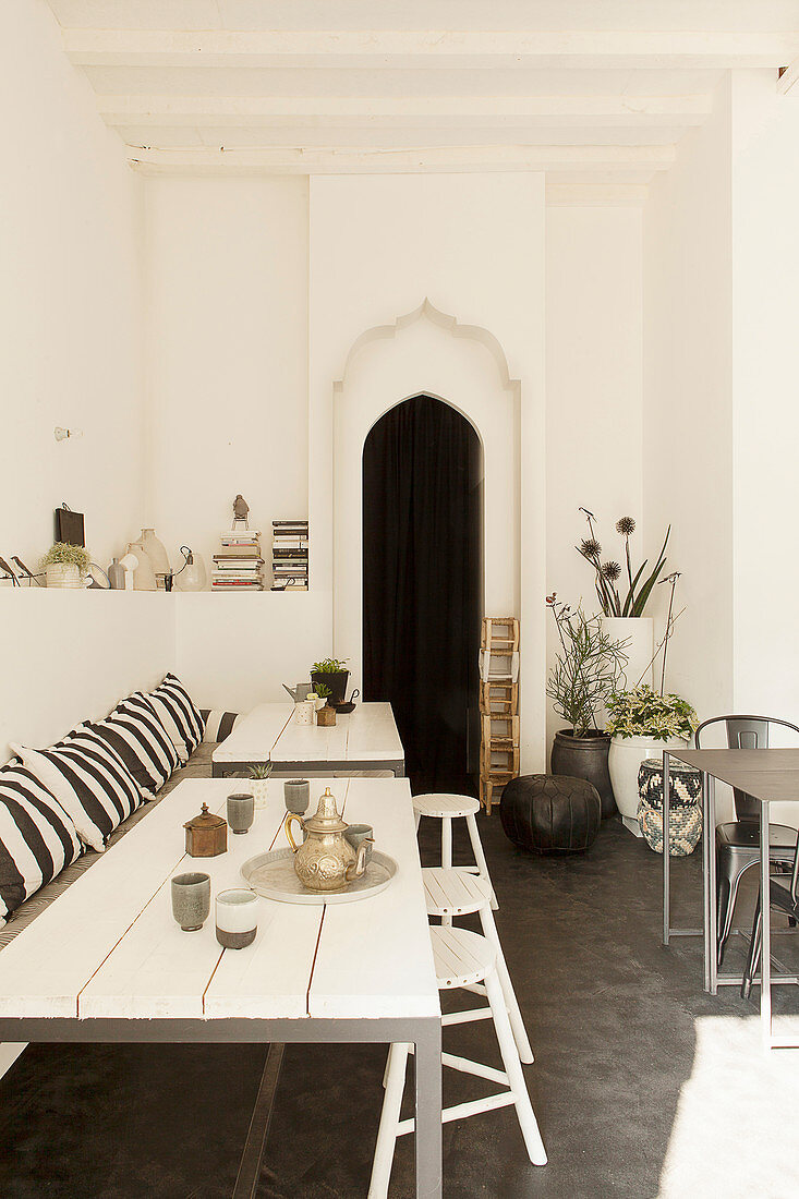 White wooden table, bench and stools in front of Moorish-style open doorway