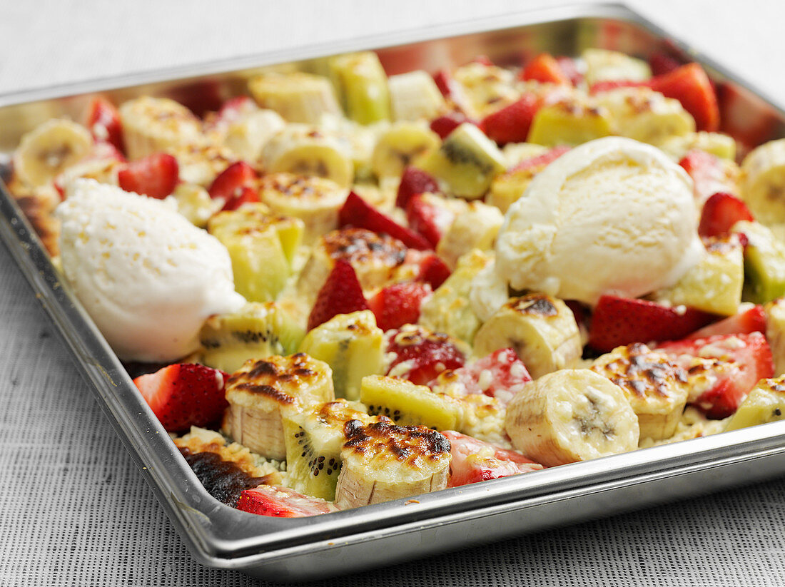 Oven-baked fruit on a baking sheet served with vanilla ice cream