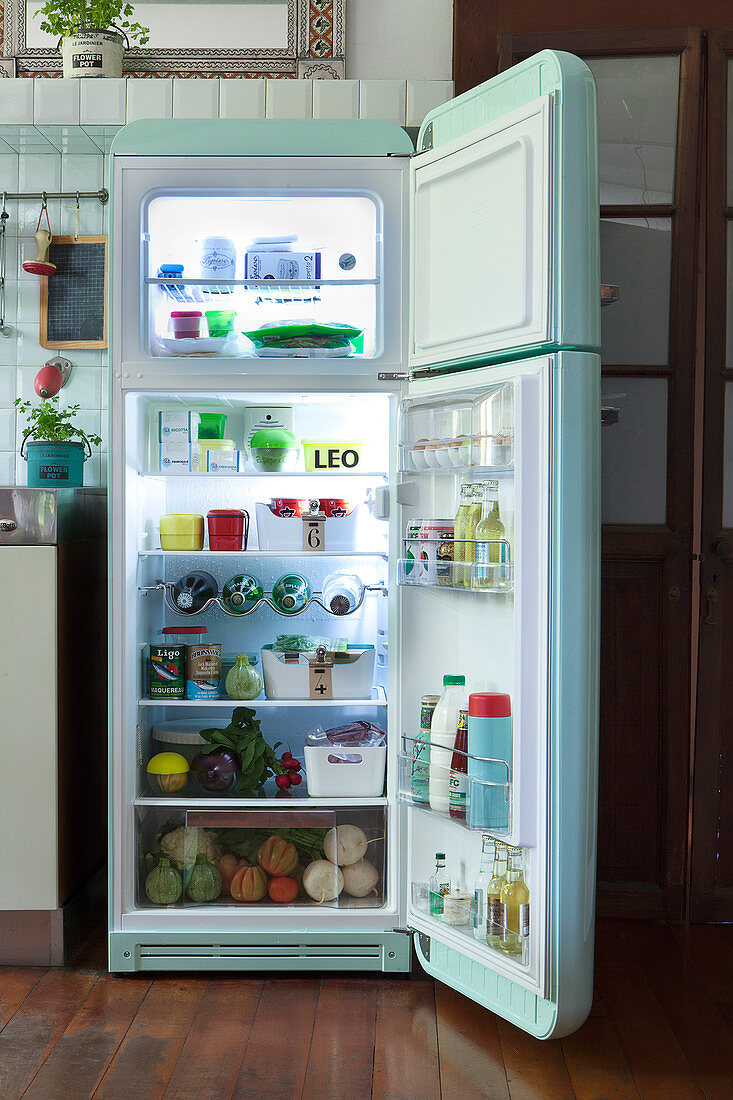 Blick in geöffneten mintgrünen Retrokühlschrank gefüllt mit Lebensmitteln