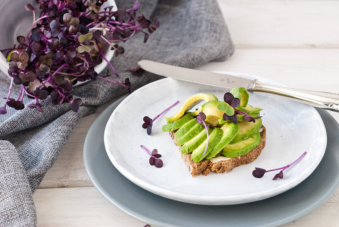 Whole grain bread topped with avocado and sprouts