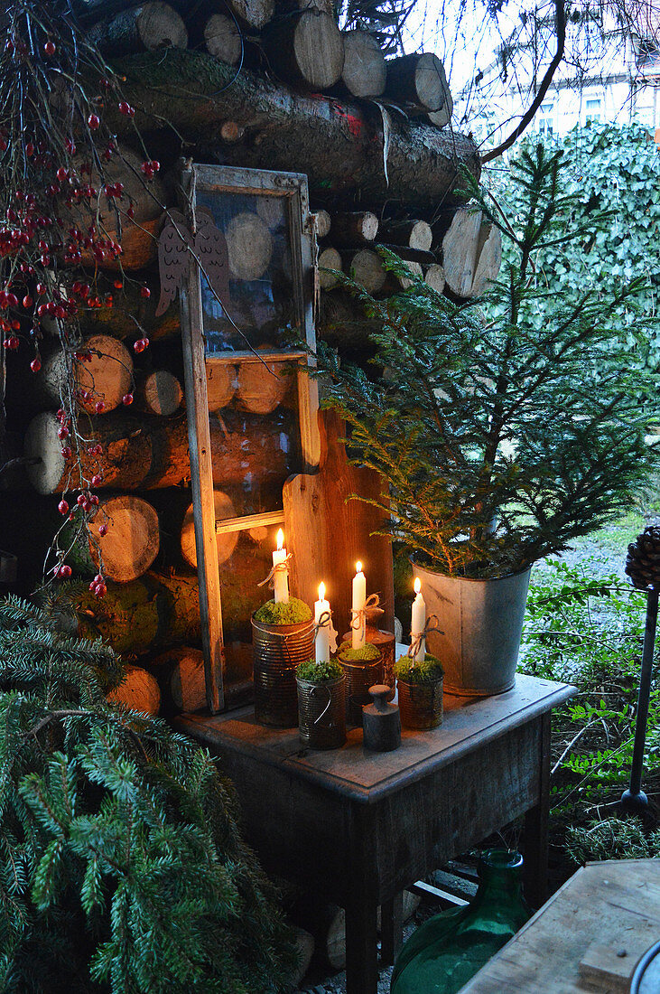Small advent decoration with spruce and old window frame on the pile of firewood
